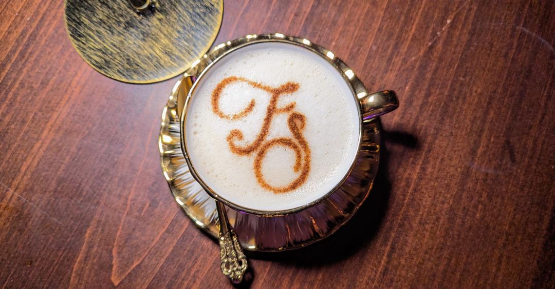 Cup of coffee with Free Spirited logo dusted on